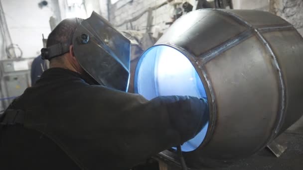 Працівник захисної маски зварювання металу на промисловому виробництві. Зварювальник зварює металеві деталі. Ремісник, який працює в гаражі металообробного заводу. Чоловіча важка робота. Ручна праця зі сталі — стокове відео