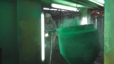 Fabrikada sanayi boyama işlemi. Boyacı özel bölmede detaylara yeşil boya sıkıyor. Üretimde çalışan güvenlik görevlisi. Uzman atölyede usta boya metali