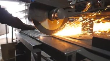 Endüstriyel imalatta çelik testeresi. Birçok parlak kıvılcım sıcak metalden uçar. Garajdaki kesim makinesini gördüm. Metal öğüten profesyonel işçilerin elleri. Yavaş çekim. Yakın çekim.