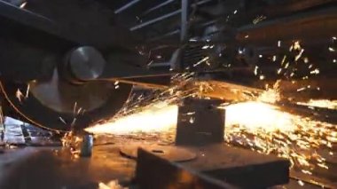 Testere kesme makinesi metali kesiyor. Birçok parlak kıvılcım sıcak metalden uçar. Garajda ya da atölyede çeliği kesen dairesel testere. Endüstriyel profesyonel imalatta öğütülen metal. Yavaş çekim