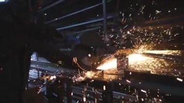 Güvenlik koruması altında çalışan işçiler metal kesmek için testere kullanıyor. Garajda çeliği kesen dairesel testereli bir adam. Metal öğüten adam. Endüstriyel üretim. Sıcak metalden kıvılcımlar çıkıyor. Dolly vurdu.