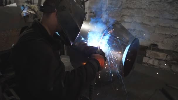 Trabajador en la construcción de metal de soldadura máscara protectora en la producción industrial. Soldador haciendo junta entre dos detalles de acero en la fábrica de metalurgia. Hombre soldando detalle de metal. Primer plano: cámara lenta — Vídeos de Stock