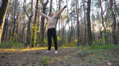 Genç adam güneşli bir ormanda amuda kalkıyor. Manzaralı ortamda güçlü jimnastik eğitimi. Yoga egzersizleri yapan bir sporcu. Sağlıklı ve aktif yaşam tarzı kavramı. Ağır çekim. Yaklaş.