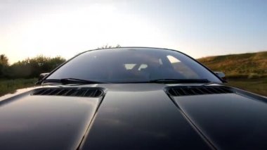 Genç çift kırsalda araba sürmekten zevk alıyor. Erkek arkadaş ve kız arkadaş yaz akşamı otomobille seyahat ediyorlar. Arka planda manzaralı otomobil sürüşü. Yolculuk konsepti. Ön görünüm