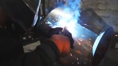 Endüstriyel üretimde koruyucu maske kaynak işçisi. Kaynakçı, metal fabrikasında iki çelik detayı arasında bağlantı kuruyor. Metal kaynak yapan adam. Yavaşça kapat.