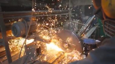 Güvenlik koruması altında çalışan endüstriyel işçiler metal parçaları kesmek için testere kullanıyor. Garajda çeliği kesen dairesel testereli adam. Metal öğüten adam. Sıcak metalden kıvılcımlar uçuşuyor. Yavaş çekim