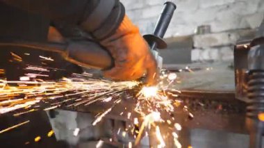 Endüstriyel işçi metal kesmek için testere kesme makinesi kullanıyor. Garajda çeliği kesen dairesel testereli adam. Metal öğüten adam. Sıcak metalden kameraya kıvılcımlar uçuşur. Yavaş çekim Dolly