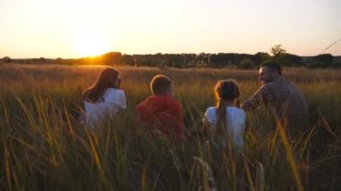 İki çocuklu genç bir aile Meadow 'da birlikte vakit geçiriyor. Küçük çocukları olan anne ve baba çimde oturup güzel doğanın tadını çıkarıyorlar. Aile mutluluğu kavramı. Dolly vurdu.
