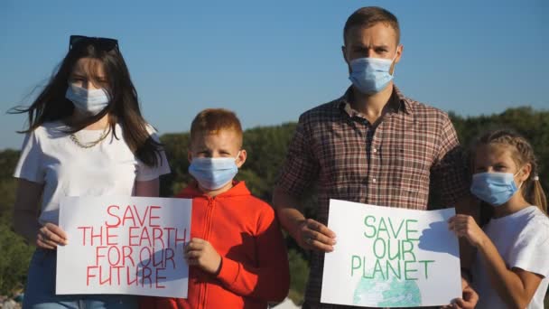 Portret van ouders met twee kinderen in handen posters van milieubeweging voor het redden van de planeet. Familie van eco-activisten in medische maskers die pleiten voor natuurbehoud — Stockvideo