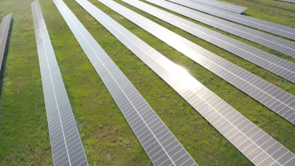 牧草地に設置された太陽光発電所の空中撮影や発電。パネルの表面に太陽の反射がある太陽農場のトップビュー。現代の再生可能エネルギー。生態学の概念 — ストック動画