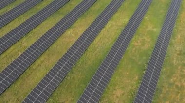 Yeşil alandaki güneş panelleri boyunca uçmak. Güneş enerjisi santrali elektrik üretir. Elektrik üreten güneş çiftliğinin hava görüntüsü. Ekoloji ve yenilenebilir yeşil enerji kavramı. Üst görünüm