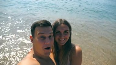 Kendi kendine portre deniz kumsalda alarak genç mutlu çift. Gülümseyen iki okyanus sahilinde selfie yapıyor. Neşeli adam ve kadın zevk balayı tatil ve deniz kenarında eğleniyor. İstirahat kavramı