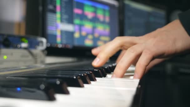 Hands of male musician playing at synthesizer at sound recording studio. Mens arms plays solo of music or new melody. Close up fingers of pianist at the piano keys. Slow motion — Video Stock