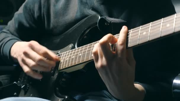 Крупним планом пальці гітариста на струнах. Чоловічі герби грають сольну рок-музику. Руки музиканта, який грає на електрогітарі. Прекрасний чорний фон на студії. Повільний рух крупним планом — стокове відео