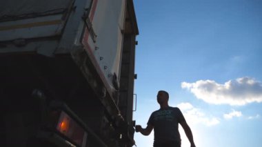 Sürücü kamyon römork için gelir ve kapıyı açar. Kamyon kırsal kesimde Park. Arka plan, güzel manzara. Alt görünümü ağır çekim yakın çekim