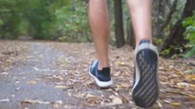 Sonbahar ormanı yolunda koşan sporcu bir adamın arka manzara bacakları. Genç sporcunun erkek ayağı doğada yol boyunca koşuyor. Dışarıdaki sporcu eğitimini takip edin. Sağlıklı aktif yaşam biçimi