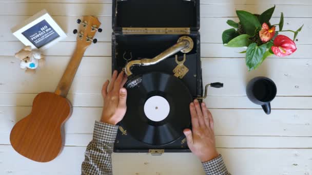 Top view on male hands turning off vintage gramophone at white table background. Arm of man taking stylus with needle from black vinyl record and closing turntable. Slow motion Close up — Video Stock