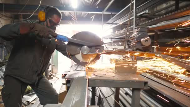 Man använder såg skärmaskin för att skära metallrör. Oigenkännlig kille med cirkelsåg sågstål i garage. Industriarbetare slipning metall. Gnistor flyger från het metall. Långsamma rörelser — Stockvideo