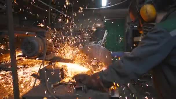 Pekerja profesional industri menggunakan mesin potong untuk memotong tabung logam. Pria yang memakai pengaman dengan gergaji melingkar menggiling baja di garasi. Manusia menggergaji logam. Sparks terbang dari logam panas. mo lambat — Stok Video