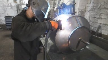 Worker in protective mask welding metal construction. Welder doing joint between two steel details. Man welding parts of the metal detail together. Industrial production manufacture. Close up