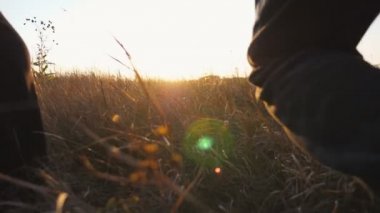 Young parents with kids holding hands of each other and running through grass field at sunset. Mother and father with two children jogging among summer meadow and enjoy to spending time together