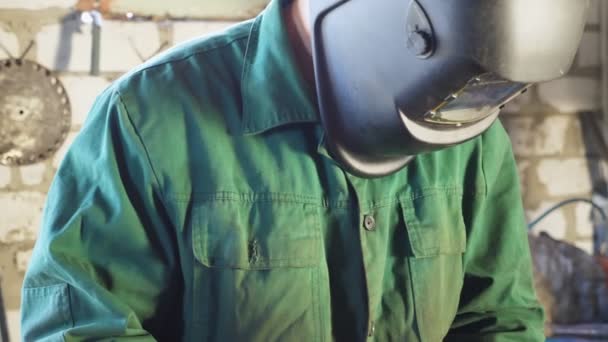 Repairman holding soldering iron and preparing to weld metal parts at garage. Male welder in protective mask working at workshop. Concept of maintenance service. Dolly shot Slow motion — Vídeo de Stock
