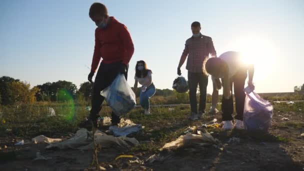 Family of eco volunteers in masks clean lawn of plastic and paper waste saving nature. Young parents and two kids in gloves collecting trash in bags near roadside. Environmental problem. Dolly shot — Stock Video