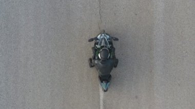 Motosikletlinin lastikleri patlatırken çok duman çıkıyor. Hareket başladığında motosiklet tekeri yolda kayıyor. Spor motosiklet çarkı asfalt yolda dönmeye başlar. Yavaş çekim Havadan çekim