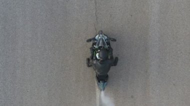 Motosikletlinin lastikleri patlatırken çok duman çıkıyor. Hareket başladığında motosiklet tekeri yolda kayıyor. Spor motosiklet çarkı asfalt yolda dönmeye başlar. Yavaş çekim Havadan çekim