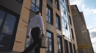 Genç kendine güvenen girişimci modern ofis binasının yakınında yürürken resmi olarak giyinir. Çantası olan başarılı bir iş adamı kaldırımda işe gidiyor. Erkek müdür işe gidip geliyor. Dolly çekim ağır çekim