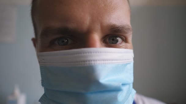 Retrato de un joven médico quitarse la mascarilla médica y sonreír. Trabajador médico quitando la máscara protectora y mirando con emoción positiva. Médico guapo con emociones y sentimientos positivos en la cara — Vídeo de stock