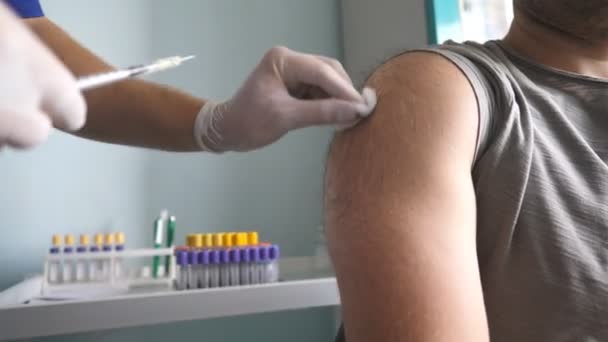 Covid-19 나 독감 백신을 투여하는 의사는 보건소에서 바이러스성 질환을 앓고 있는 남성 환자에게 주사를 했습니다. 병원에서 백신 주사를 맞고 있어요. 면역 자극. 예방 접종 개념. 닫아 — 비디오