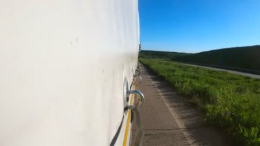 Kamyon kargo karavanının yan tarafı kırsalda hareket ediyor. Asfalt yolda mal taşıyan bir kamyon. Güneşli bir yaz gününde sanayi arabası hedefe doğru gidiyor. Lojistik kavramı. Yavaş çekim