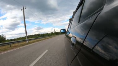 Otomobiller güzel manzaralarda geziniyor. Kırsal bir otoyolda araba sürerken yakalanmış. Siyah araba yaz günü yol boyunca ilerliyor. Yol seyahati kavramı. Yavaş çekim