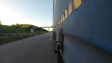 Asfalt yolda mal taşıyan bir kamyon. Kırsal kesimde hareket eden bir kamyon römorkundan diğerine bir bakış açısı. Hedefe giden ticari bir araba. Kargo taşımacılığı kavramı. Zaman aşımı