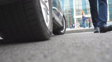 Kızı dışarı otomatik bacaklar. İş adamı açar ve yüksek topuklu ayakkabı güzel genç kadın için arabanın kapısını tutar. Şoför kadın yolcu için otomobil kapı açma. Yakın çekim