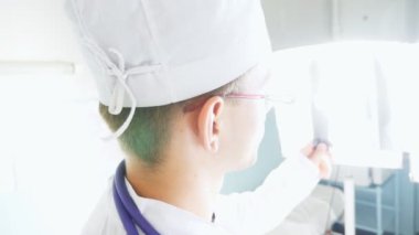 Kafkasyalı iki doktor MRI resmine bakıp bunu tartışıyor. Erkek doktorlar röntgen görüntülerine bakarken birbirlerine danışıyorlar. Hastanedeki tıp çalışanları röntgen izlerini inceliyor. Arka plan görünümü
