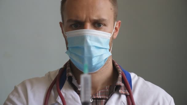Portrait of doctor in protective mask pouring liquid from syringe and tapping on it. Hospital employee preparing drug for injection. Medical worker testing medicine. Vaccination and COVID-19 concept — 비디오