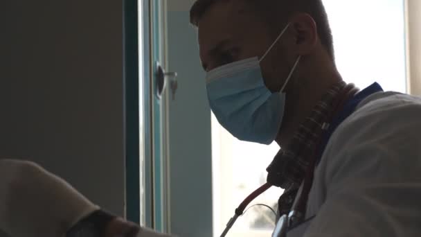 Um médico cansado a bater com as mãos na mesa. Cientista masculino usando luvas médicas e máscara trabalhando com tubos de ensaio em laboratório. Médico a verificar amostras de sangue para COVID-19. Conceito de pandemia de coronavírus — Vídeo de Stock