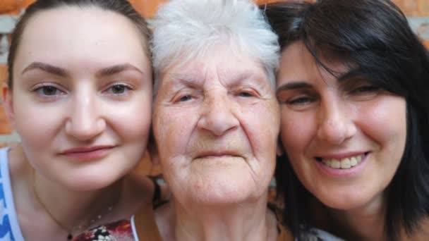 Portret starszej kobiety z córką i wnuczką patrzących razem w kamerę. Szczęśliwe panie okazujące radosne emocje na twarzach. Pozytywny wyraz twarzy kobiet. Powolny ruch Zamknij — Wideo stockowe