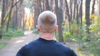 Orman yolunda koşan tanınmayan bir adam. Erkek sporcu doğada çalışıyor. Atletik adam dışarıda kardiyo eğitimi alıyor. Sağlıklı aktif yaşam tarzı kavramı. Yavaş çekim Arka planı kapat