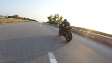 Güneşli bir sonbahar gününde otoyolda motosiklet süren motosikletliyi takip edin. Motosikletli, kır yolunda motosikletiyle yarışıyor. Yolculuk sırasında bisiklet süren bir adam. Yolculuk kavramı. Hava görüntüsü