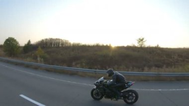 Anayolda motosiklet süren motosikletliyi takip edin. Motosikletli, kır yolunda motosikletiyle yarışıyor. Yolculuk sırasında bisiklet süren adam. Yolculukta özgürlük ve macera kavramı. Hava görüntüsü