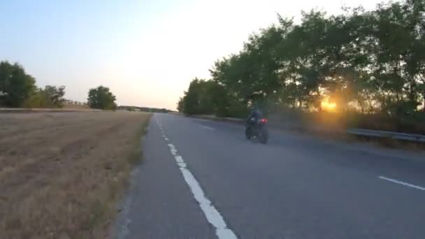 跟随骑摩托的人在日落时骑着现代摩托车在乡间路上.骑摩托车的人在高速公路上骑摩托车.旅行时骑自行车的家伙。旅行和自由的概念。空中射击 — 图库视频影像