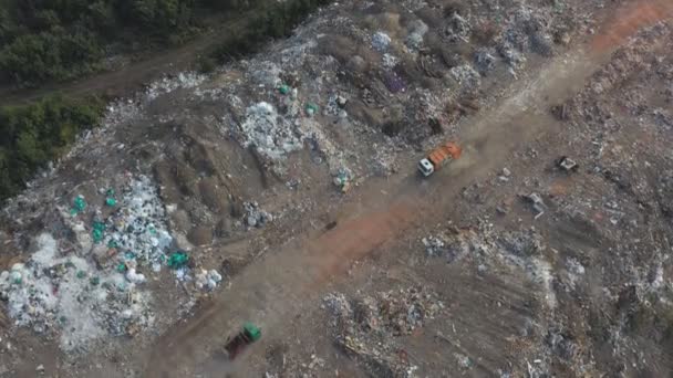 Flying over industrial trucks dumping trash at open places at nature. Aerial shot of big rubbish pile lying among field in countryside. Global environmental pollution problem. Top view Slow motion — Stock Video