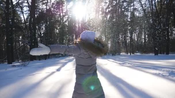 Menina alegre desfrutando de belo dia de inverno no prado da floresta nevada. Mulher feliz jogando neve e caindo apreciando o tempo de inverno. Senhora bonito ter emoções alegres ao ar livre. Conceito de inverno. Devagar. — Vídeo de Stock