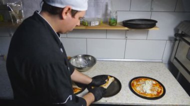 Eldivenli erkek aşçı mutfakta lahanayla lezzetli pita ekmeği paketliyor. Üniformalı genç aşçı restoranda lezzetli lavaş servis etmeye hazırlanıyor. Yemek pişirme kavramı. Üst Görünüm Yavaş Çekim