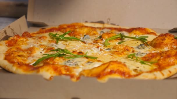 Mână de bucătar bucătar în mănușă de finisare pizza vegetariană gustoasă, cu un presărat parmezan ras la restaurantul din bucătărie. Mâncare delicioasă coaptă într-o cutie de carton la pizzeria de bucătărie. Închide mișcarea lentă — Videoclip de stoc