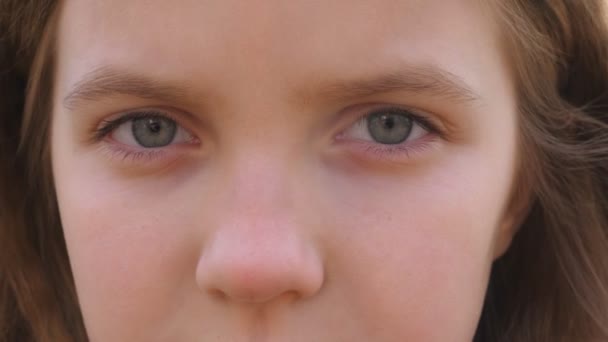 Close up blue eyes of unhappy little blonde girl blinking and looking into camera with a despairing sight. Sorrowful gaze of small depressed child. Facial expression of disappointing female kid — Stock Video