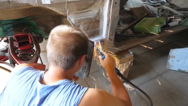 Неузнаваемый ремонтник носит защитную маску сварки некоторые детали авто. Механик работает в гараже или мастерской. Человек занимается обслуживанием автомобилей. Концепция ремонта и обслуживания автомобилей. Долли выстрелил — стоковое видео